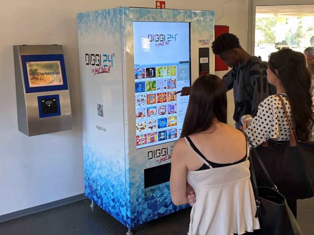 Schülerinnen und Schüler am DIGGI 24 Snackautomaten in der Schule