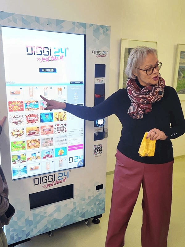 Frau wählt Snacks am Touchscreen eines DIGGI 24 Automaten für Schulen